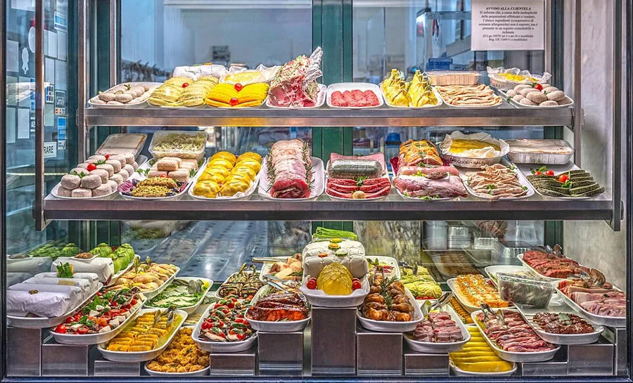 Refrigerated deli display case with trays of prepared food