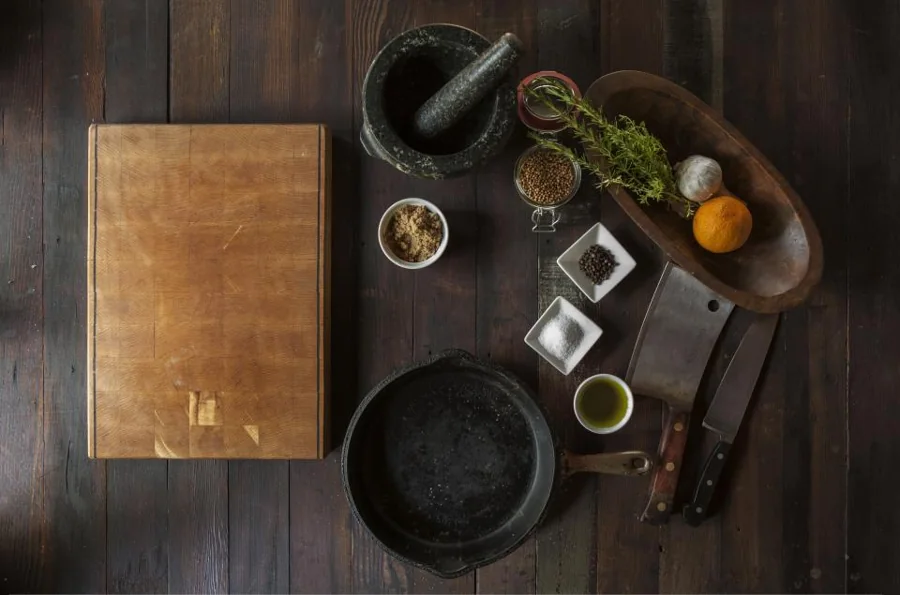 Cast iron pan, cutting board and kitchen utensils on a dark table