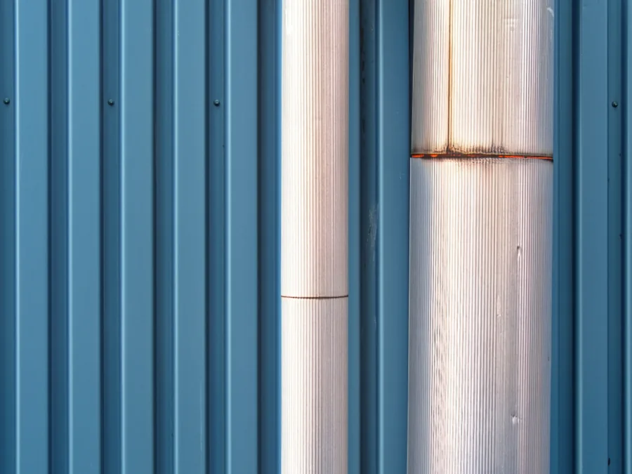 Stainless steel pipes against a blue corrugated wall